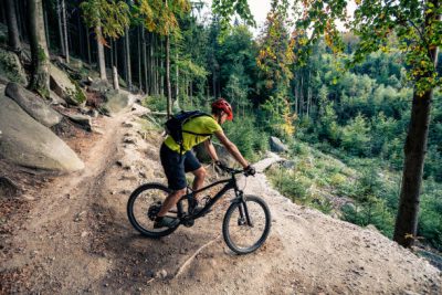 Cycling in autumn inspirational mountains landscape. Mountain biker riding on bike on forest dirt trail. Man cycling MTB on enduro track. Sport fitness motivation and inspiration.